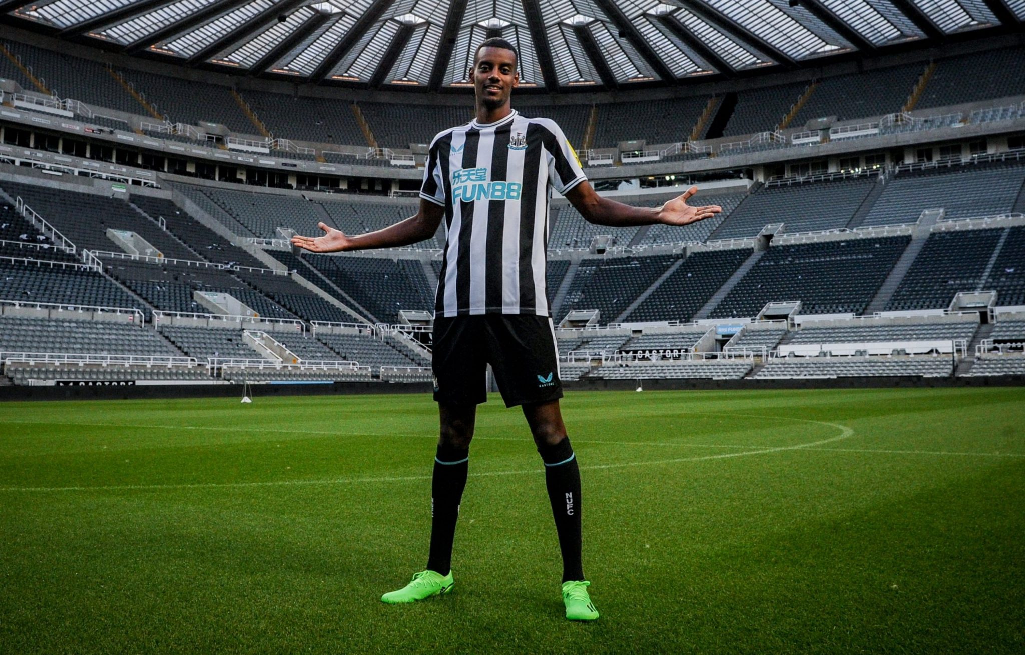  The image shows a football player, Alexander Isak, in a black and white Newcastle United shirt, celebrating a goal he has just scored against Tottenham Hotspur at St James' Park.